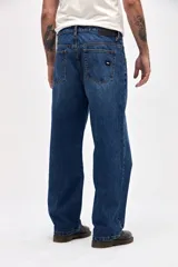 Jean de corte holgado en cadera, cintura y piernas, con diseño clásico de cinco bolsillos y cierre frontal con botón y cremallera.