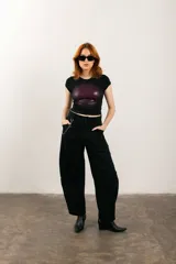 Pantalón negro de corte ancho con bolsillos laterales y cadena metálica decorativa.