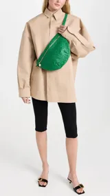 Riñonera verde tejida con cierre dorado y correa ajustable.