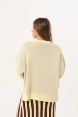 Sweater color manteca de tejido de punto con cuello redondo y ribete marrón. Presenta dos peces marrones tejidos en el frente con detalles bordados a mano.