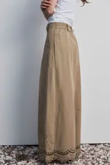 Pantalon de pierna ancha y tiro alto color marron, con bordado en contraste que recorre el ruedo y detalles en calado.