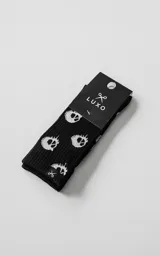 Medias de caña media color negro con estampado de calaveras blancas tejidas. Presentan tejido acanalado y etiqueta pequeña con logo de tijera en el borde superior.