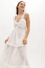 Vestido largo blanco de gasa de algodón con textura liviana. Tiene escote en V con nudo central, breteles con voladitos y falda con frunces.