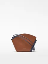 Bandolera marrón de piel bovina con cuerpo formado por dos piezas asimétricas entrecruzadas. Tiene un compartimento con cierre de cremallera, asa larga extraíble y logo grabado.