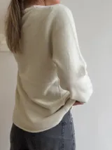 Sweater de punto de corte holgado y diseño minimalista, con cuello redondo y mangas largas. Presenta una textura suave y un largo que llega por debajo de la cadera.