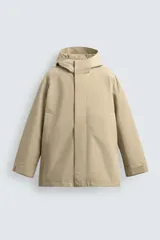 Trench de corte relajado confeccionado en tejido técnico con mezcla de algodón. Presenta cuello subido con capucha, cierre frontal con cremallera oculta por botones a presión, bolsillos de vivo en la cadera y mangas largas con puños ajustables mediante trabillas.