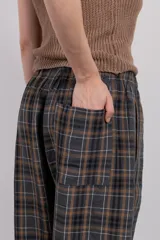 Pantalón cuadrillé de tiro bajo y silueta amplia, con cintura elástica, bolsillo trasero y calce levemente más ajustado en los tobillos.