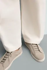 Zapatilla urbana de hombre confeccionada en piel con acabado de serraje, diseño minimalista con cordonera oculta y suela de goma a contraste.