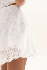 Pollera corta de encaje blanco con diseño de volados escalonados y cintura elástica.