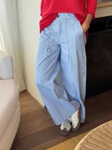 Pantalón celeste de corte amplio con cintura alta y pinzas. Detalle de pespuntes en zigzag color rojo en la parte delantera.