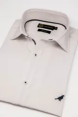 Camisa de manga larga entallada de la marca Club House, color celeste, con diseño slim fit, cuello corto y detalles de ribete oscuro en la línea interior del cuello. Cuenta con bordado sutil de un ave en la parte inferior.