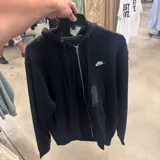 Campera tipo hoodie negra con cierre frontal completo, capucha con cordones ajustables y logo de Nike bordado en blanco en el pecho.