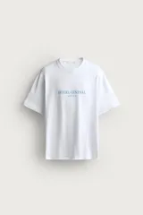 Remera blanca de corte relaxed fit con cuello redondo y manga corta. Presenta un estampado frontal en color celeste con el texto "HOTEL CENTRAL" acompañado de cinco estrellas.