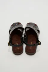 Sandalias planas de cuero sintético marrón, con tiras cruzadas en el empeine y tachas metálicas doradas distribuidas por toda la capellada. Cuenta con tira ajustable en el talón con hebilla.
