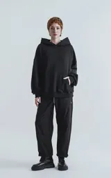 Hoodie oversize de algodón, color negro, con capucha forrada, bolsillo frontal tipo canguro y bolsillo con cierre en la manga estilo bomber.