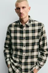 Camisa de corte relaxed fit confeccionada en una mezcla de lana y algodón. Presenta un diseño de cuadros, cuello solapa, manga larga con puños abotonados y cierre frontal con botones.