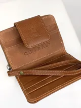Mini billetera de cuero color marrón con textura combinada, lisa y efecto croco en la solapa. Cuenta con cierre perimetral, múltiples ranuras para tarjetas y una correa de muñeca extraíble.