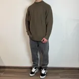 Sweater verde oliva de tejido grueso con cuello alto y mangas raglán. Corte holgado.