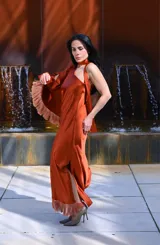 Vestido midi color ocre, con escote halter, lazo al cuello y detalle de flecos en el ruedo.