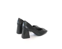 Zapatos de tacón de cuero negro, con punta cuadrada, aplique metálico en el empeine y tacón ancho de altura media con textura geométrica.