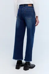 Jean de pierna ancha, tiro alto, color azul oscuro con desgaste en los muslos y ruedo desflecado.