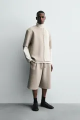 Sudadera de corte oversize confeccionada en tejido técnico de algodón con elasticidad, cuello redondo y manga corta. Presenta una tacha metálica decorativa en la parte posterior.