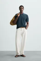 Polo de manga corta color verde azulado oscuro, confeccionado en tejido de punto con textura. Presenta cuello solapa y cierre frontal de botonadura.