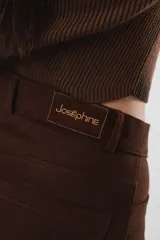 Pantalón marrón acampanado de tiro medio, con bolsillos delanteros y traseros. Cierre frontal con cremallera y botón.