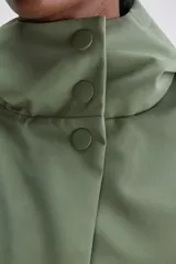 Campera de calce relajado y silueta amplia color verde, con capucha integrada, cierre frontal con cremallera oculta por cartera de broches y bolsillos delanteros con solapa.