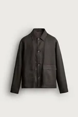 Sobrecamisa relaxed fit confeccionada en tejido de lino de color negro, con cuello solapa, manga larga con puño abotonado, bolsillos de plastrón en la cadera y cierre frontal de botones.