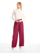 Pantalón tipo palazzo de corte ancho y fluido, confeccionado en tejido sastrero. Presenta tiro alto con doble abotonadura frontal, pinzas decorativas y cintura elástica en la parte posterior. Incluye bolsillos laterales funcionales.