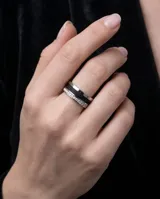 Anillo de acero plateado con banda central negra texturizada, detalles de números romanos y una hilera de circonias.