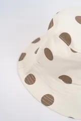 Gorro tipo bucket color crema con estampado de lunares fucsias.