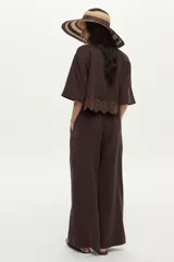 Pantalón de lino marrón de corte ancho y relajado, con pinzas frontales, bolsillos y lazo ajustable en la cintura.