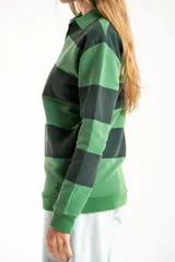 Sweater de punto con diseño de rayas horizontales anchas en tonos verde oscuro y verde claro, con cuello tipo polo y cierre frontal parcial. Presenta mangas largas con puños elásticos y un pequeño bordado en la parte inferior.
