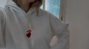 Canguro color crudo de algodón con felpa, de corte holgado y diseño con capucha. Presenta un bordado pequeño en el centro del pecho acompañado de un aplique de piedras en forma de corazón.