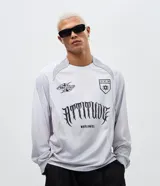Remera de manga larga estilo deportivo con corte boxy, confeccionada en poliéster. Presenta cuello redondo, paneles laterales en tejido texturizado y estampados gráficos estilo tribal y lettering gótico en el frente.