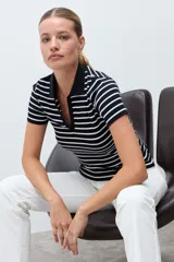 Remera de tejido canalé a rayas horizontales blancas y negras, con cuello polo y escote en V sin botones, de manga corta y corte ajustado.