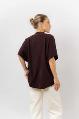 Sweater de tejido de punto color negro, con cuello semi alto y mangas cortas amplias. Presenta una silueta relajada y caída fluida.