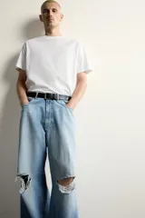 Jeans baggy fit de corte holgado en denim de algodón celeste, con tiro medio, cinco bolsillos, roturas en las rodillas y cierre frontal con cremallera y botón.
