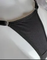 Tanga less roja de algodón con tiras laterales regulables mediante arandelas y reguladores metálicos.
