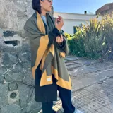 Ruana de material símil cachemira, de diseño bicolor en tonos gris y lila con bandas anchas en los bordes.