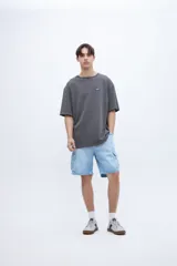 Remera blanca de algodón con calce oversize, teñida en prenda, con parche chico en el pecho y diseño fotográfico de dos tragos en la espalda.