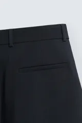 Pantalón de corte relajado en color verde militar, con diseño de pliegues frontales, bolsillos laterales y cierre de cremallera con botón.