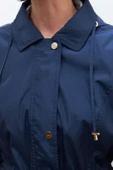 Campera impermeable azul marino con capucha desmontable, cierre frontal con botones a presión y cordón ajustable en la cintura.
