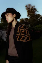 Saco tejido de punto con diseño de guarda inca en la parte superior. Presenta bolsillos frontales con detalles de tiras de cuero y flecos. De corte recto y largo medio, con terminaciones en tejido acanalado.