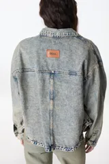 Campera de denim celeste con efecto lavado, corte recto, cuello camisero, cierre frontal con botones metálicos, bolsillos de parche en el pecho y laterales.