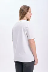 Remera blanca de algodón con estampado de flores rosadas y texto en celeste.