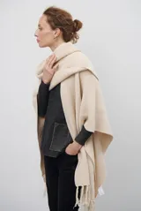 Ruana de tejido de punto en color negro, con diseño de cuello alto y terminaciones con flecos en los bordes.