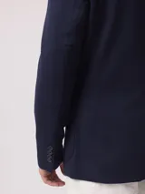 Saco color beige de piqué con cuello con solapas y bolsillos de plastrón. Mangas con coderas y bajo con abertura en espalda.